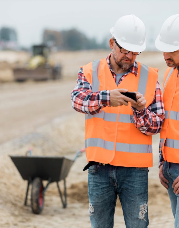 Two builders checking road construction plan on the phone