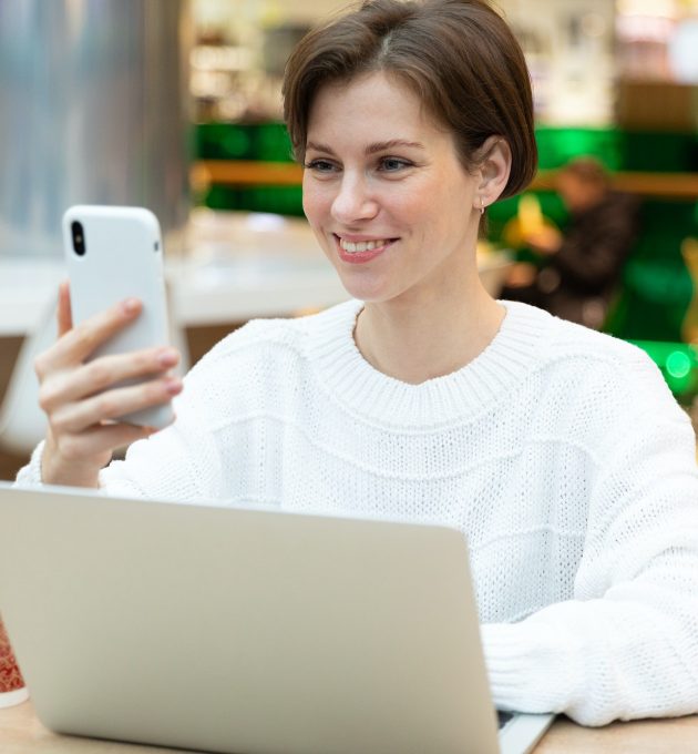 young woman working on a laptop receives a cheerful message and smiles